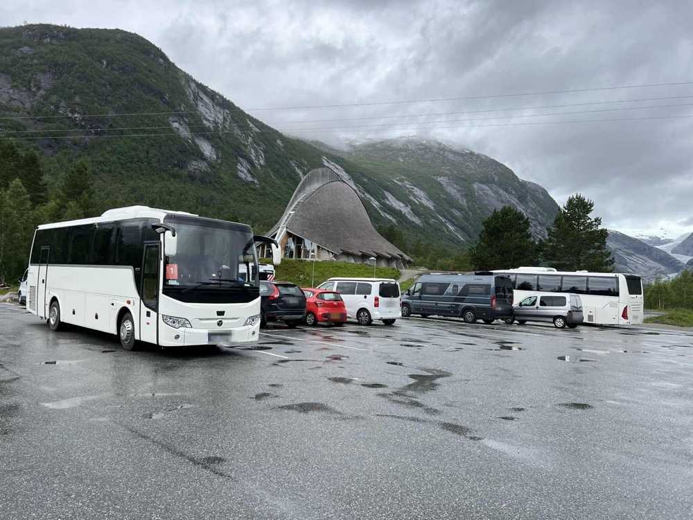 A coach and several minibuses parked in front of the tent-shaped glacier visitor centre under low cloud