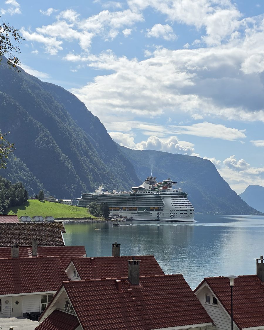 A cruise ship alongside at Skjolden in summer sunshine beneath steep green fjord walls