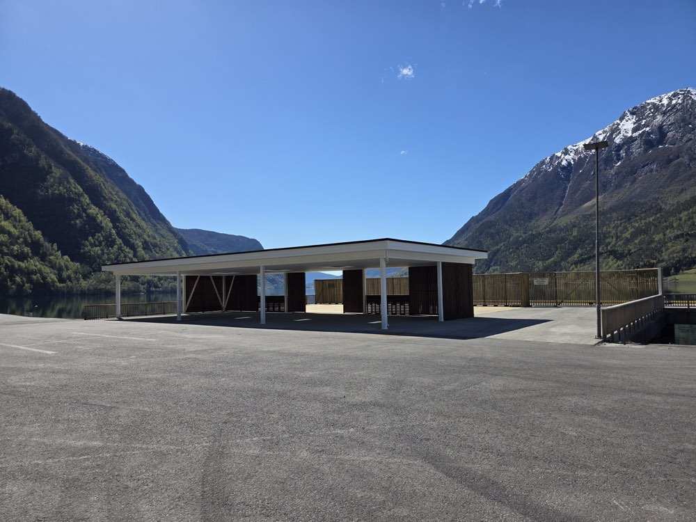 The open-sided market pavilion on the quay, with the fjord and mountains framed between its columns