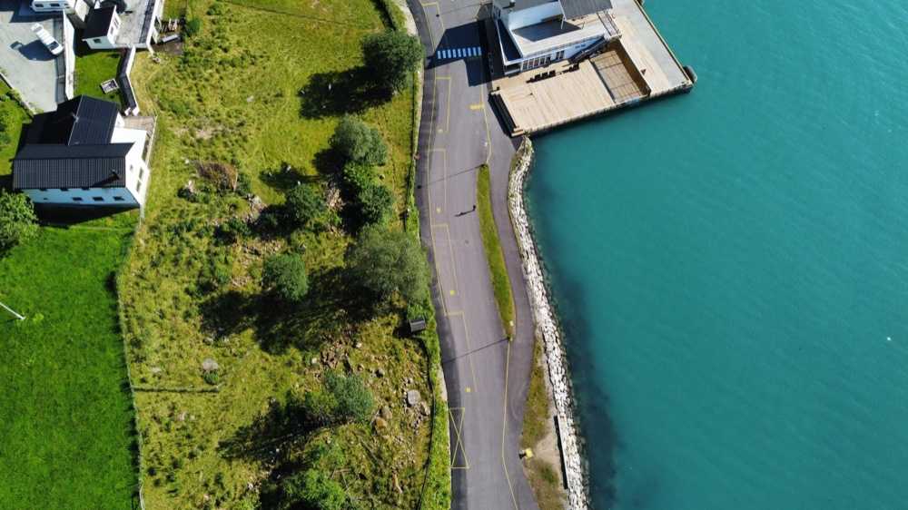Linear coach parking bays numbered 10 to 13 painted along the shore road, with the shorex pavilion deck and the pier at the top of the frame