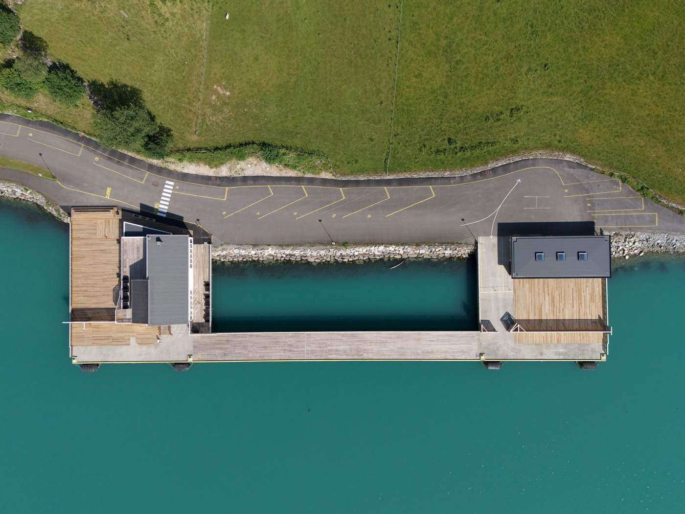 The cruise pier from directly above: angled coach bays numbered 2 to 8 marked in yellow along the apron, linear bays beyond them, a white pedestrian crossing to the terminal, the turning area with its direction arrow, and the pier itself running out into turquoise water