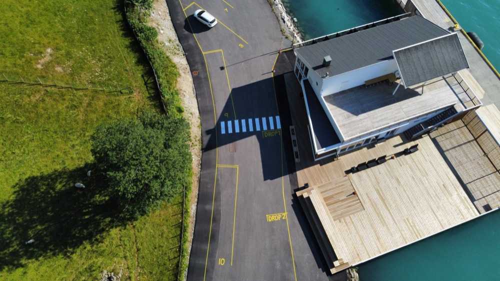 The terminal building and its timber deck from directly above, with the blue-striped crossing marked DROP 1 leading to the entrance, DROP 2 marked further along the kerb, and coach bays 7 to 10 numbered in yellow on the apron opposite