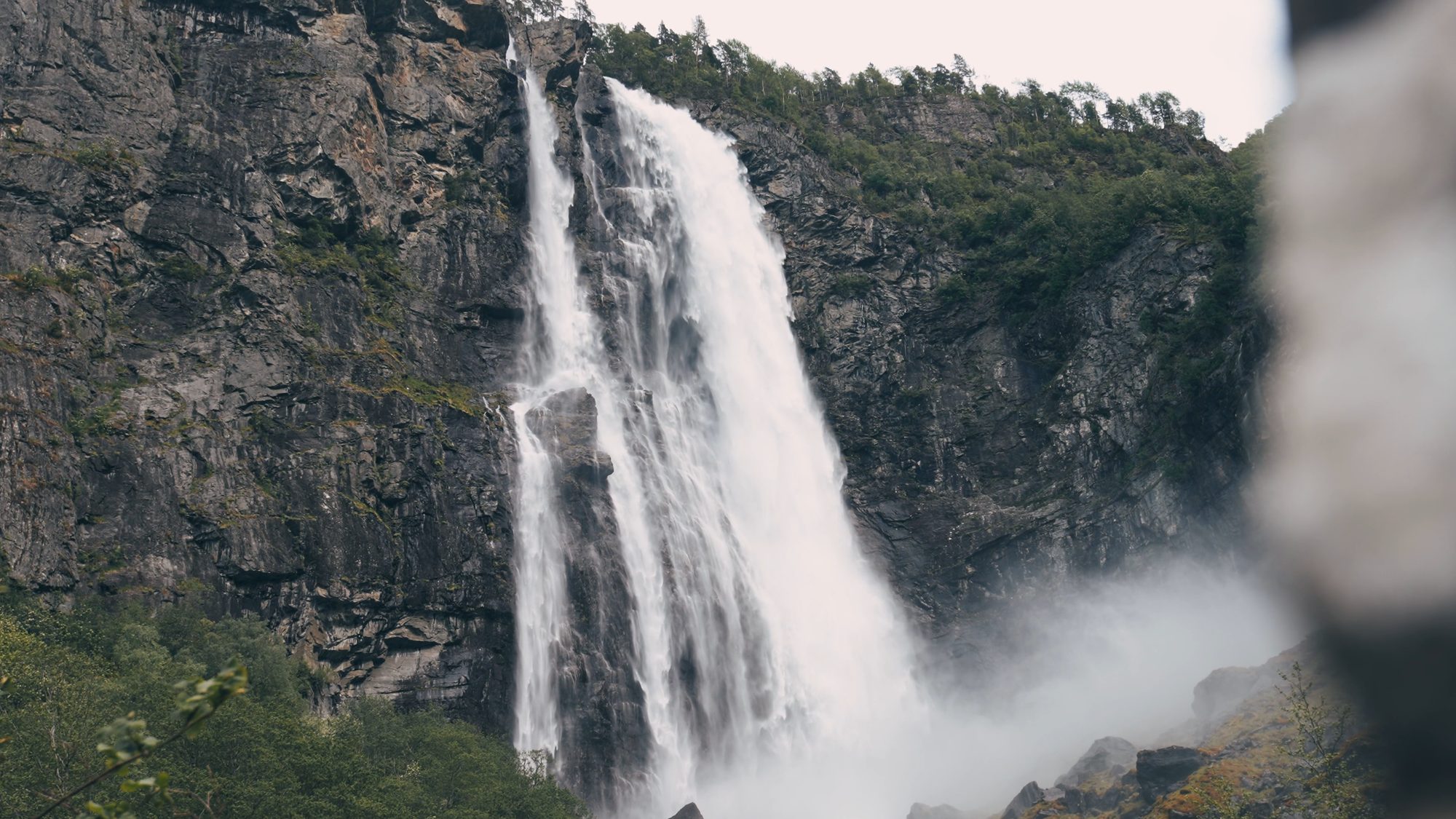 Feigefossen close up at the end of the walk: the waterfall pouring off the rock wall into a cloud of its own spray