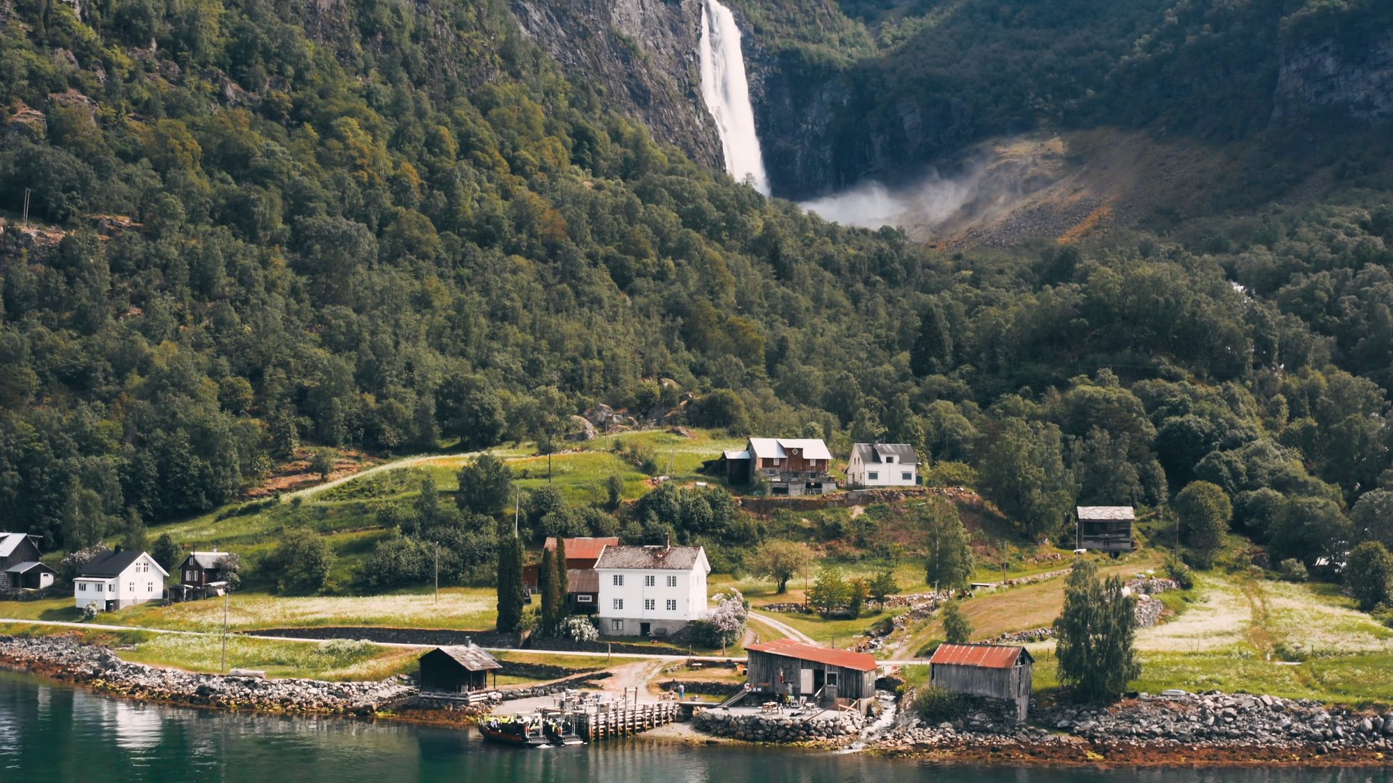 Feigum from the air: a small farm on the fjord shore, and above it Feigefossen falling in one long white line down the mountainside