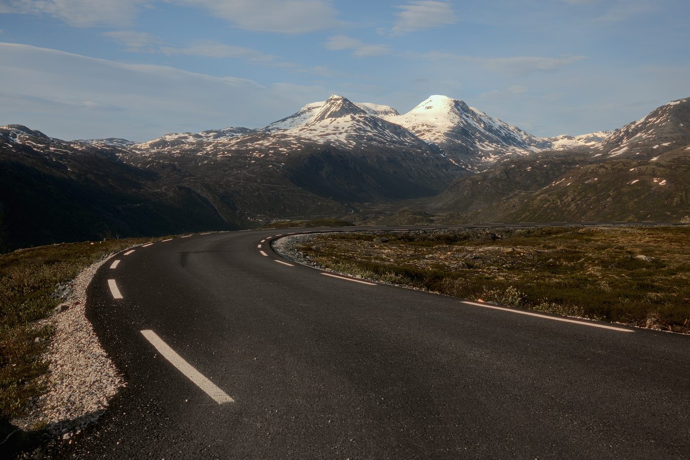 The Sognefjell road crossing the high plateau towards snow-capped summits — the road the Ice Tunnels excursion drives