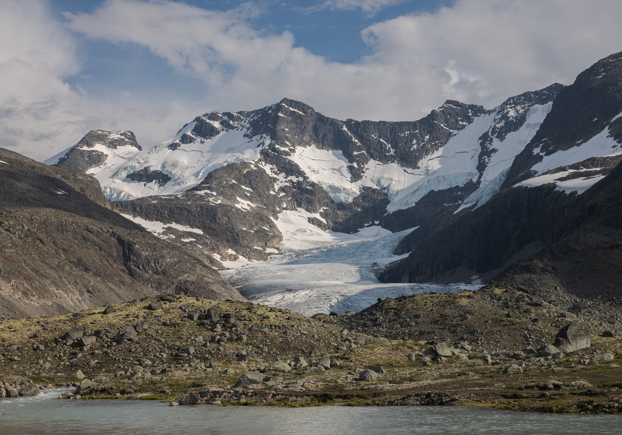 The Hurrungane rising over the approach to Styggedalsbreen, the glacier lying in the saddle between the peaks and a tarn in the foreground