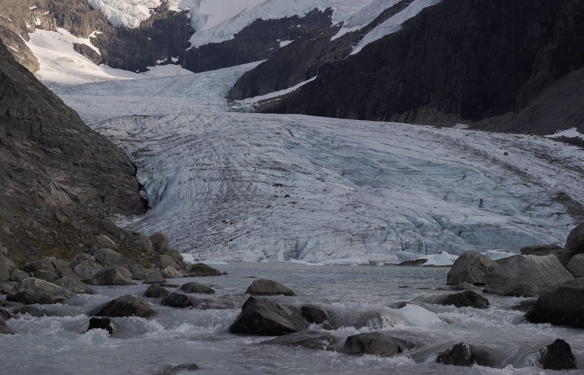 Meltwater running between boulders at the foot of Styggedalsbreen, the glacier's crevassed surface above